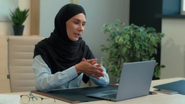 Mutlu Arap iş kadını Müslüman iş kadını tesettürlü kadın işkadını kadın işveren müdürü danışman öğretmen konuşma video konferansı bilgisayarlı internet iletişimi.