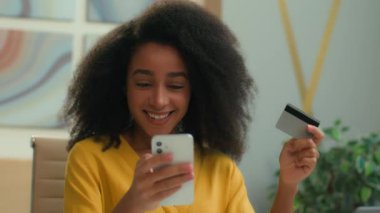 Mutlu Afro-Amerikan iş kadını müşteri müşteri iş kadını neşeli kız kredi kartı ile kolay alışveriş gülümsüyor akıllı telefon ödeme emri ofisten online banka parası satın alıyor