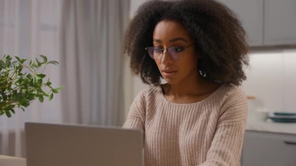 アフリカ系アメリカ人女性若いミレニアルガールフリーランサーは キッチンでオンラインウェブサイトを閲覧するラップトップコンピュータPcを使用してメガネで女性のビジネスマンから遠隔仕事 — ストック動画