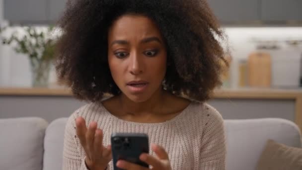 Chockad Ledsen Flicka Afroamerikansk Kvinna Soffan Håll Smartphone Tittar Mobiltelefon — Stockvideo