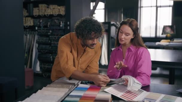 多种族顾客寻找纺织品样品讨论设计理念阿拉伯裔印度男性推销员白人女性买家选择面料的颜色用于工作室的服装制作 — 图库视频影像