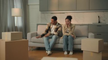 Üzgün Afrikalı Amerikalı erkek kadın kiracılar apartmandan taşınıyor. Hayal kırıklığına uğramış erkek koca, kanepe üzerinde kadın eş. Banka kredisi borcu olan emlak kredisi yüzünden üzgün.