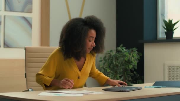 アフリカ系アメリカ人女性がオフィスに座ってテーブルデスクトップのビジネスウーマン雇用主マネージャー労働者女性ビジネス女性女性は オープンラップトップのタイピングコンピュータの朝の仕事を職場で始める — ストック動画