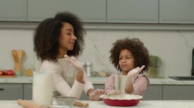 Mutlu aile Afro-Amerikan kadın anne, küçük kız çocuğuyla yemek pişiriyor, birlikte yemek pişiriyor, birlikte yemek pişiriyor, beş takım çalışması yapıyor pasta hamuru dağıtıyorlar.