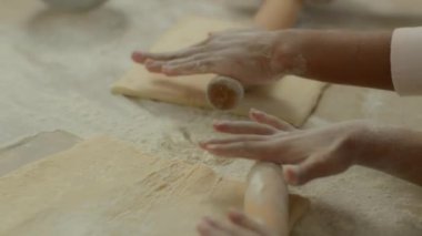 Aile mutfakta iki kişi el ele tutuşur. Kadın kolları birbirine sarılır. Tanınmayan bir kadın, kız çocuğuna hamur yoğurmayı öğretir.
