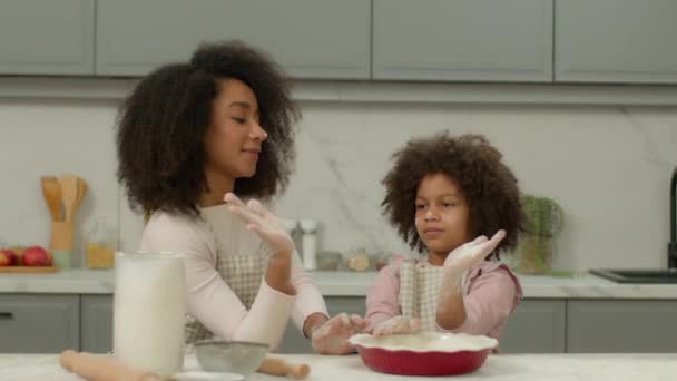 ハッピーファミリーアフリカ系アメリカ人女性の母親は 家庭のキッチンで一緒に料理を楽しんでいる小さな娘の子供ガールと料理し ハッピーな5チームワークの小麦粉ベーキングペストリーケーキ生地の食品配達 — ストック動画