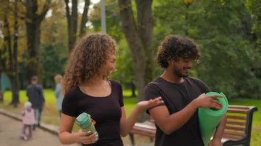 Mutlu Arap genç Hintli erkek Kafkas kadın yoga minderi tutuyor, dışarıda egzersiz yapıyor, parkta yürüyor, aşık çiftler, kız arkadaş şehirde spor sonrası aktif yaşam tarzı hakkında konuşuyor.
