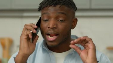 Kızgın sinirli Afrikalı etnik adam cep telefonuyla kötü konuşma yapıyor evde öfkeli adam akıllı telefon portresi bağırıyor, bağırıyor, sorun var diye bağırıyor.
