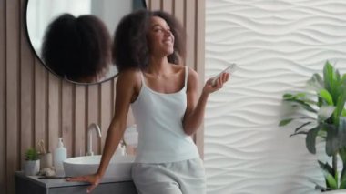 Afro-Amerikan gülen mutlu kadın komik haber cep telefonu eğlencesi gülüşü videolu telefon konferansı kızı banyodaki sosyal medya esprilerini izlerken sevinç gülümsemesi.
