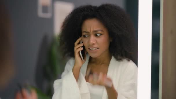 怒っている感情的な欲求不満 ストレス アフリカ系アメリカ人女性 イライラした民族的な女性 女性の粉末 家庭の浴室で鏡を見ている有機化粧スキンケア 電話の対立を話す — ストック動画