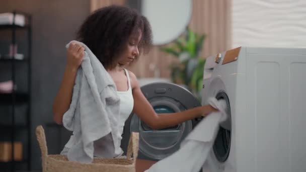アフリカ系アメリカ人女性 忙しい タオル 洗濯機 洗濯機 洗濯室 コンディショナー — ストック動画