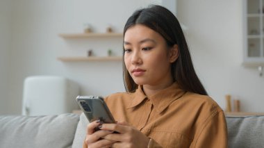 Koreli Çinli çok ırklı kadın akıllı telefon uygulaması kullanıyor internet sosyal medya dalgın Asyalı ev kadını mutfakta cep telefonu mesajı yazıyor evde sipariş teslimatı satın alıyor