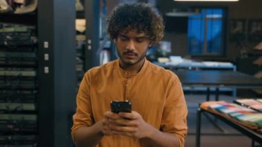 Hintli Arap etnik adam odaklı müşteri müşteri alıcısı cep telefonu akıllı telefon konuşmaları internet alışverişi erkek moda tasarımcısı atölyede online sipariş tekstil