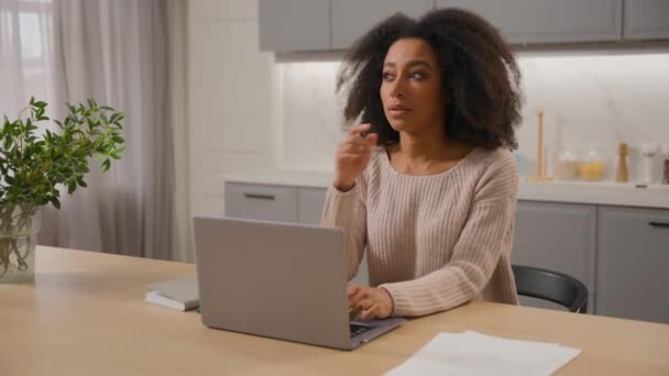 アフリカ系アメリカ人女性フリーランサー キッチンでラップトップと自宅で働く 若い民族少女 ビジネスマン ペンシブ思考 コンピュータの遠隔研究に関する記事を入力するアイデアを作成します — ストック動画