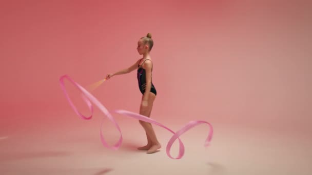在舞蹈演播室的艺术体操项目中 白人小女孩杂技表演的孩子女青少年跳舞的年轻运动员体操运动员带着体操粉带旋转 — 图库视频影像