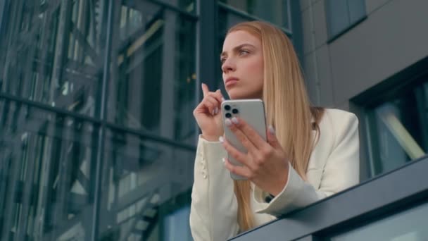 以严肃的 沉思的高加索女人为焦点 在办公室附近用手机思考女商人想出了一个主意 想在智能手机上写上时间表 — 图库视频影像