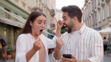 Kafkasyalı mutlu çift, heyecanlı erkek kadının keyfini çıkarın. Şanslı zafer, cep telefonu, akıllı telefon mesajları. İyi haberler.