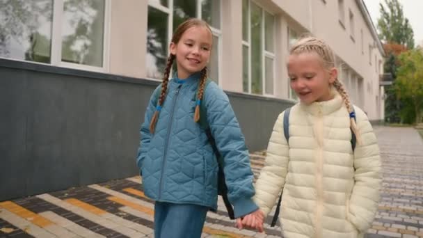 2人の小さな女の子の友人姉妹のクラスメイトが外で街の街を歩いていて 話し合いの会話をしたり ニュースを話したり 子供たちに話しかけたり 話したりする — ストック動画