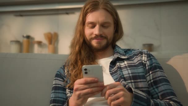 快乐的微笑无忧无虑的积极放松的白种人男人男人呆在家里沙发上舒服的沙发上使用手机滚动社交应用媒体笑着看智能手机网 — 图库视频影像
