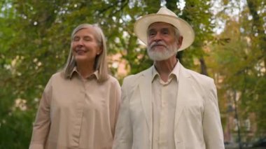 Mutlu Kafkasyalı büyükanne ve büyükbaba emekli çift emekliler, gülümseyen kadın adam birlikte gezintiye çıkıp şehir dışındaki doğa parkı hakkında konuşuyorlar. Neşeli yaşlı çift kadın erkek muhabbeti Parkland 'ın dışında yürümenin keyfini çıkarın.