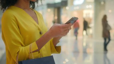 Tanımlanamayan bir kadın elinde cep telefonu, cep telefonu, mesajlaşma, internet üzerinden sanal alışveriş merkezleri hafta sonu, paketler, kadın alıcı moda tüketicisi, teknoloji harcıyor.