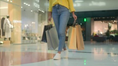 Önden bakan kadın çantalarla alışveriş merkezine gidiyor tanınmayan bir alışveriş mağazası satın alıyor modaya uygun marka moda kıyafetler alıyor yeni cuma koleksiyonu para harcıyor.