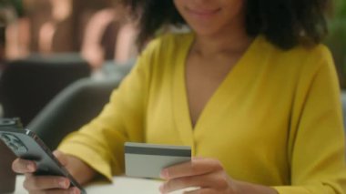 Genç Afrikalı Amerikalı bir kadının elinde akıllı telefon, banka kartı, ödeme alışverişi mutlu bir bayanın nakit para birimi bankası, finans satın alma, internet üzerinden işlem aleti var.
