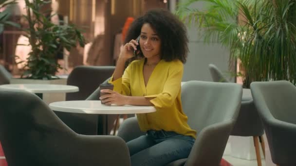 Mujer Afroamericana Sentada Cafetería Hablando Teléfono Móvil Teléfono Celular Sosteniendo — Vídeos de Stock