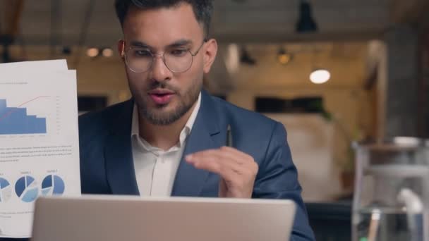 笑顔の男 インドのアラビアのビジネスマン男 男性コンサルタントマネージャー ビジネスコーチ 話し合い ラップトップ上のオンライン相談ビデオ通話 営業図 オフィスで分析するグラフ — ストック動画