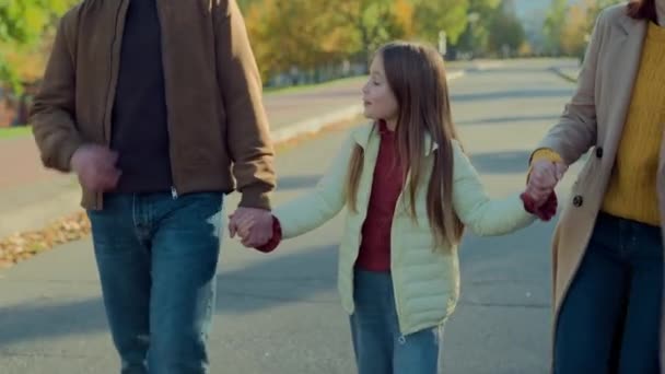 白种人快乐的家庭监护周末在城市秋季公园的户外度假一起聊天的小女孩和父母牵着手去学校 — 图库视频影像