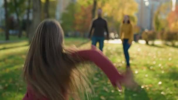 快乐的白种人家庭在公园里父母和小孩在户外玩游戏秋天的女儿跑着爸爸抱着爸爸在空中打转有趣的玩耍一起玩着快乐的假期 — 图库视频影像