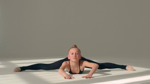 ダンススタジオバレエスクールの床にエアロビクスを伸ばすリトルガールジム選手コーカサス女子アクロバットバレリーナダンサー子供は 分割位置曲げ柔軟性ジムナスティックスポーツに座っています — ストック動画