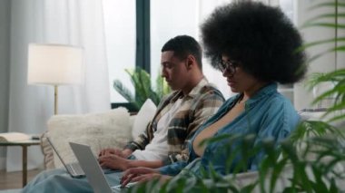 Gadget video oyunu bağımlısı aile bilgisayarları evdeki kanepede oturan Afro-Amerikan çifti, iki dizüstü bilgisayar kullanmadan, üzgün, Afro-Amerikalı kadın, kadın, erkek, stres nefes alıp veriyor.