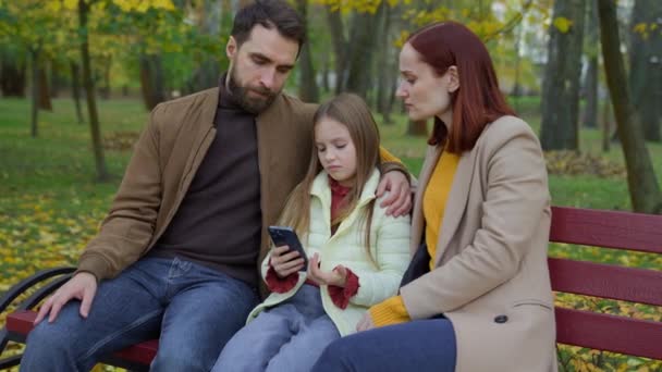 Sonbaharda Şehir Bankında Birlikte Oturan Beyaz Bir Aile Cep Telefonuyla — Stok video