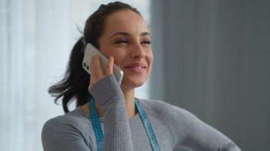 Beyaz tenli, formda, formda, yoga yapan, spor salonunda kilo vermiş, cep telefonuyla konuşan, neşeli, beslenme uzmanı, akıllı telefonlu, gülümseyen bir kadın.