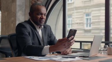 Mutlu iş başarısı, Afrikalı Amerikalı yetişkin menajer, orta yaşlı şaşırmış, heyecanlı erkek işçi, ofis işadamı, etnik işadamı, işveren cep telefonu zaferi, iyi haber ödülü.
