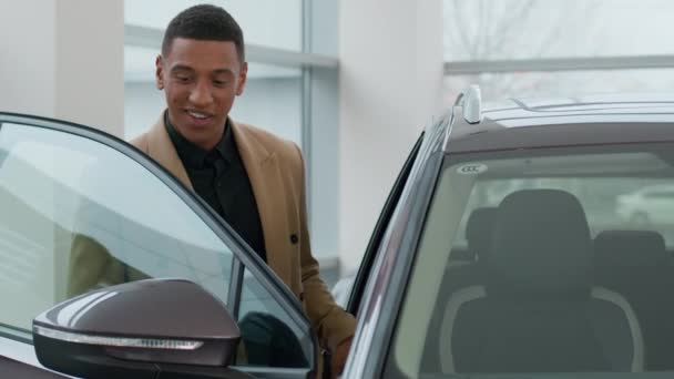 アフリカ系アメリカ人男性顧客男性バイヤーリッチビジネスマン幸せなクライアントはショールームサロンディーラーストアモーターショーテストドライブ自動車の車の中で車の新しい電気自動車の中に座っている現代自動車を選択します — ストック動画