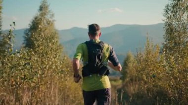 Dağdaki yeşil çayır vadisinde koşan tanımlanamayan beyaz erkek. Tecrübeli dağcı yürüyüşçü sporcu yürüyüşü dışarıda spor aktiviteleri spor sağlık eğitimi.