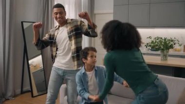 Kapatın Afrikalı mutlu aile evde dans ediyor baba erkek anne kadın bakıcı aile el ele tutuşarak sevimli evlat edinilmiş küçük çocuk çocuk heyecanlı hissediyor
