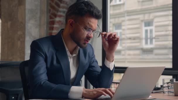 阿拉伯裔印度商人疲倦了 不舒服的家伙经理在办公室工作时使用笔记本电脑生病的男性商人揉揉干痒的眼睛 眼部疼痛摘下眼镜 视力不好 健康问题 — 图库视频影像