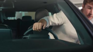 Kafkasyalı iş adamı sürücü erkek, yeni modern elektrikli arabanın kapısını açık bırakıp otomobil el hareketlerini kutluyor. Evet, başarıyı kazan. Kiralık araba alırken mutlu bir şekilde gülümse.