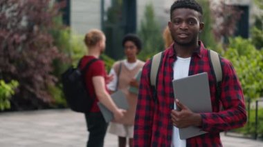 Mutlu gülümseyen Afro-Amerikan öğrenci erkek erkek başparmak göstererek harika tepkiler veriyor. İyi bir eğitim öneriyor. Şehir üniversitesinde poz vermek ve çok kültürlü öğrencilerle konuşmak gibi.