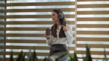 Kafkasyalı, mutlu, dans eden, ofis işkadını, mola ver. Kulaklık takıp müzik dinle. Kulaklık tak, kulaklık tak, kahve iç.