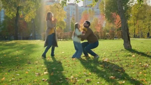 白种人快乐的家庭周末假日大自然在城市的秋天公园里与爱的父亲一起举着小孩的女儿旋转旋转旋转着旋转着玩着好玩的游戏的母亲欢呼着 — 图库视频影像