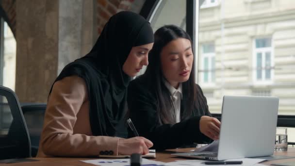 两名女商业女学生女孩多种族女多民族女商人亚裔韩籍女上司导师教帮助穆斯林伊斯兰实习生在头巾同事中讨论文件团队合作 — 图库视频影像