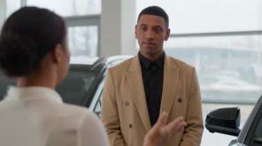 Afro-Amerikalı erkek müşteri dinle kadın satıcı araba galerisinde müşteriye danışmanlık yapıyor. Lüks otomobil sohbet otomobili kiralama hizmeti kredisi satın almayı tartışıyor.