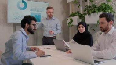 Erkek lider, takım arkadaşlarıyla konuşuyor. İş arkadaşları, ofis konferansında iş sunumu yapıyor. İş adamları ve iş kadını, veri analiz stratejisi pazarlama stratejisini tartışıyor.
