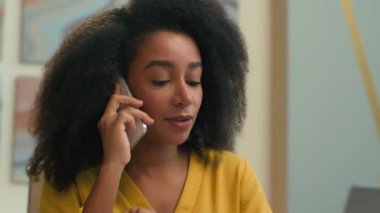Afro-Amerikalı etnik kadın iş kadını gülümsemesi mutlu iş kadını işkadını danışman yönetici patron iş yerinde cep telefonuyla konuşuyor online danışma akıllı telefon görüşmesi