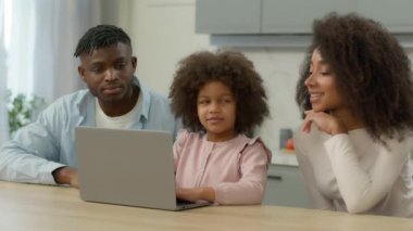African American family at kitchen shopping online together mother father teach child daughter little girl at home kitchen using laptop food delivery kid computer playing e-learning parental control