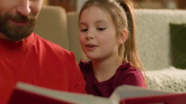 Caucasian family read book together at evening home smiling man parent dad babysitter father help children kids daughters with homework little school girls reading learn knowledge elementary education